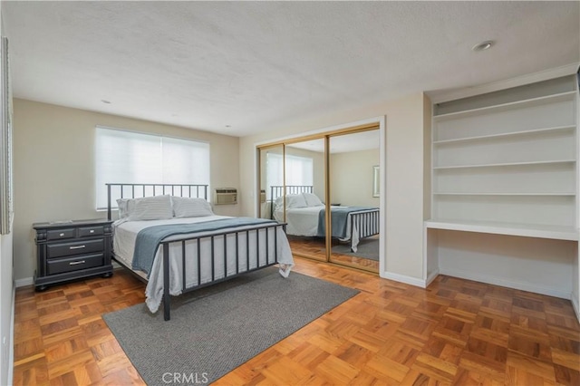 bedroom featuring dark parquet floors, a wall unit AC, and a closet