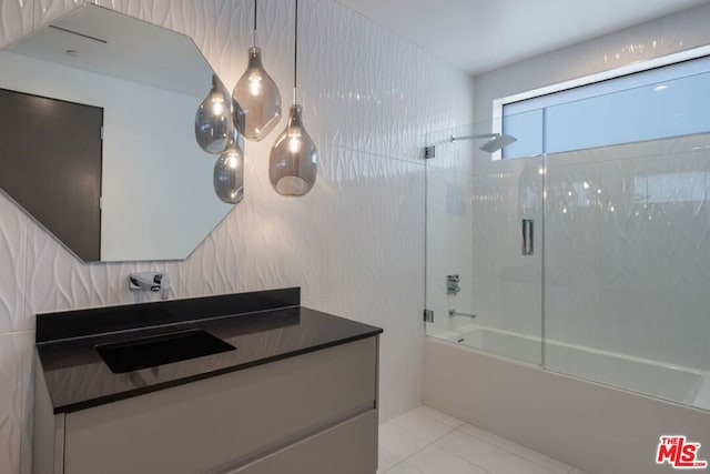 bathroom with tile patterned floors, vanity, enclosed tub / shower combo, and tile walls