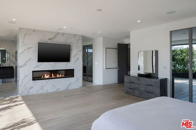 bedroom featuring access to outside, a premium fireplace, and light hardwood / wood-style floors