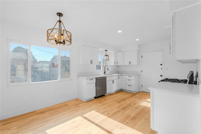 kitchen with appliances with stainless steel finishes, sink, decorative light fixtures, white cabinets, and light hardwood / wood-style floors