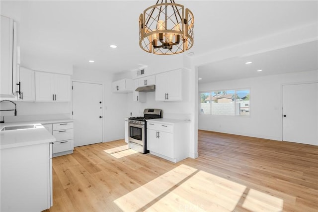 kitchen with gas stove, sink, white cabinets, and decorative light fixtures