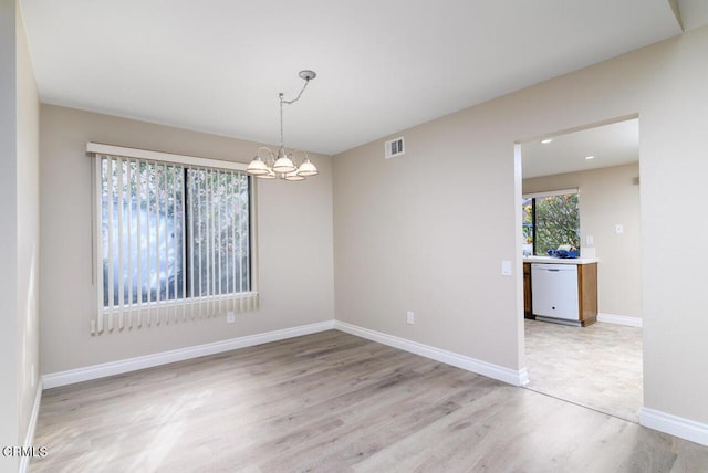 spare room with light wood-type flooring and a chandelier