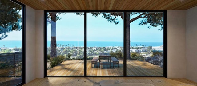 doorway with hardwood / wood-style floors, a water view, and wooden ceiling