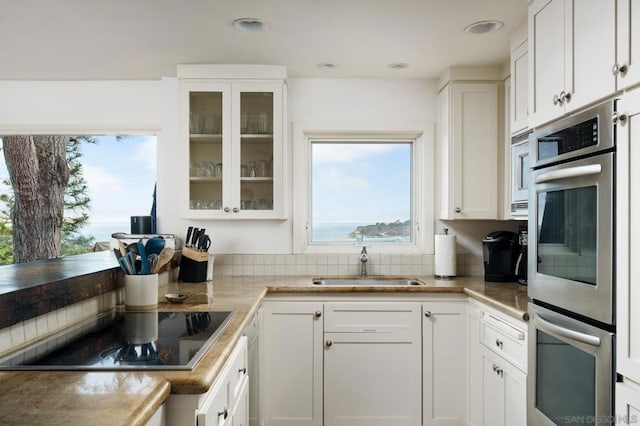 kitchen featuring black electric cooktop, sink, white cabinets, and a healthy amount of sunlight