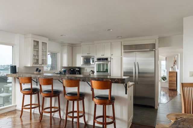 kitchen featuring built in appliances, dark hardwood / wood-style flooring, white cabinetry, and a wealth of natural light