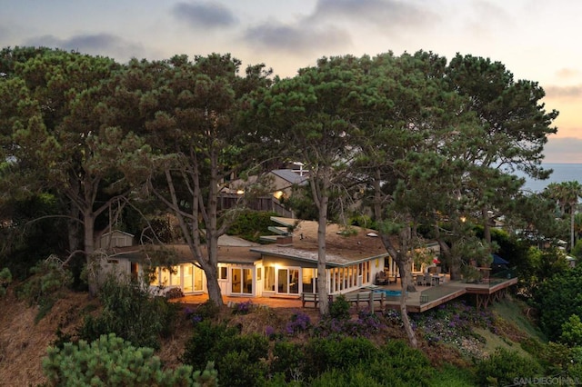 back house at dusk featuring a deck