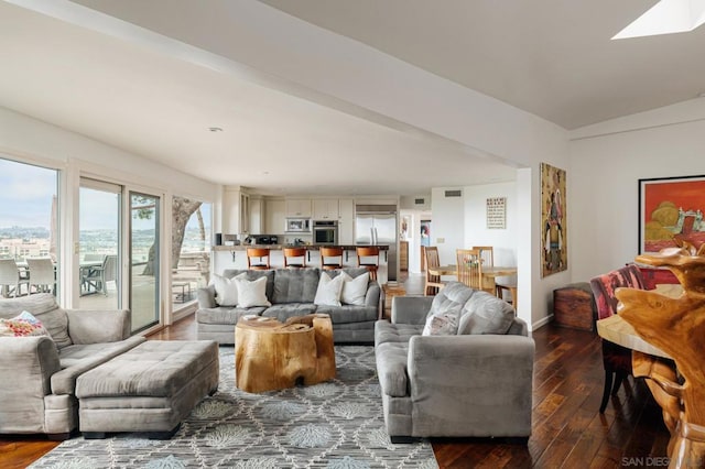 living room featuring vaulted ceiling with skylight and hardwood / wood-style flooring