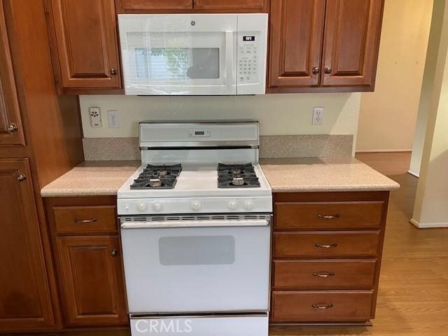 kitchen featuring white appliances and light hardwood / wood-style flooring