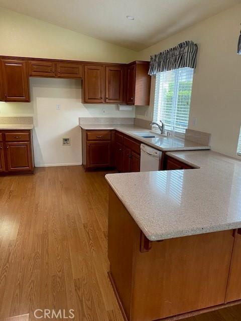 kitchen with kitchen peninsula, a kitchen breakfast bar, light hardwood / wood-style flooring, dishwasher, and lofted ceiling