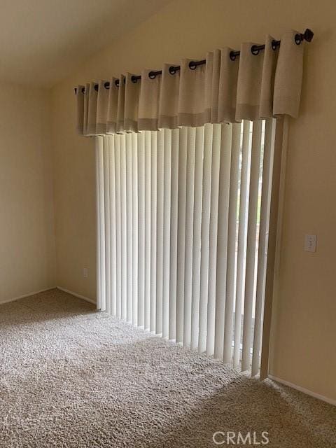 empty room featuring carpet flooring, vaulted ceiling, and radiator