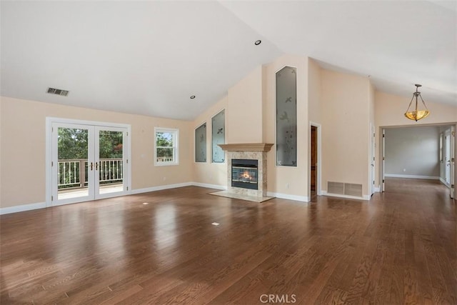 unfurnished living room with vaulted ceiling, a fireplace, french doors, and dark hardwood / wood-style floors