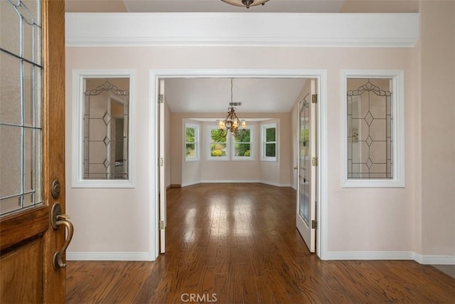 foyer entrance featuring a notable chandelier, dark hardwood / wood-style flooring, and crown molding