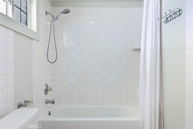 bathroom featuring toilet and shower / bathtub combination with curtain