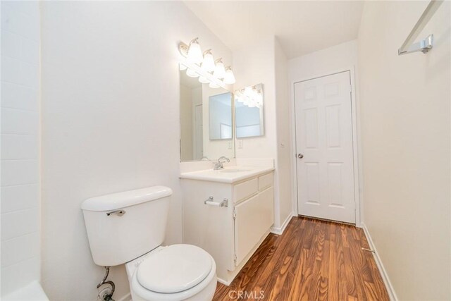 bathroom featuring wood-type flooring, toilet, and vanity