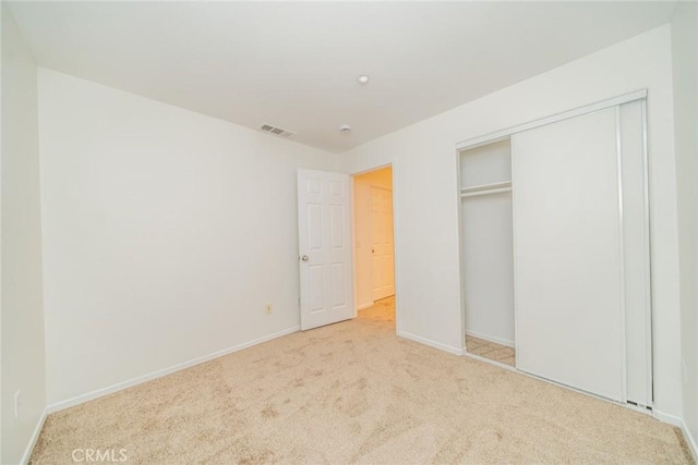 unfurnished bedroom featuring light carpet and a closet