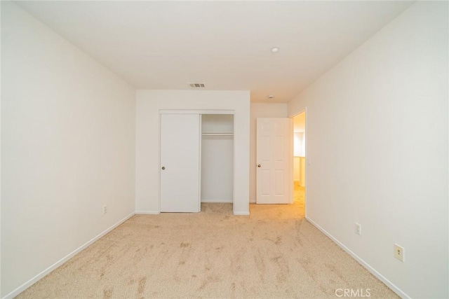 unfurnished bedroom with light colored carpet and a closet