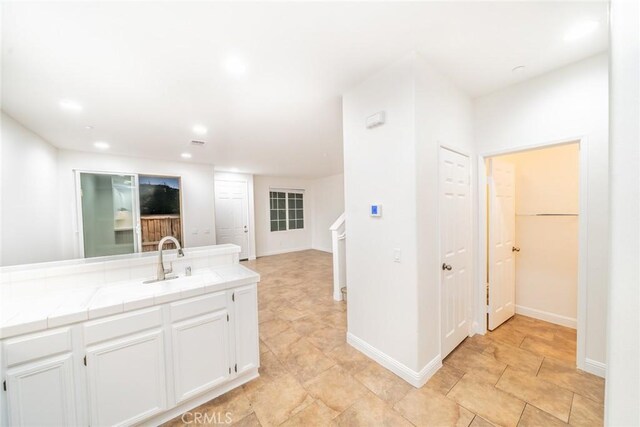 kitchen featuring tile countertops, white cabinets, and sink