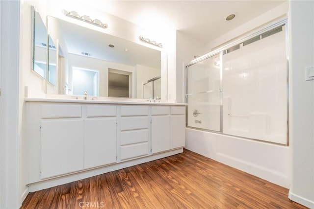 bathroom featuring bath / shower combo with glass door, wood-type flooring, and vanity