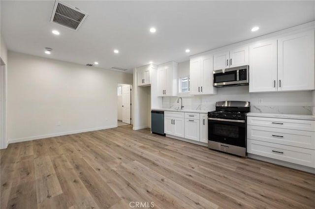 kitchen with white cabinetry, sink, light wood-type flooring, and appliances with stainless steel finishes