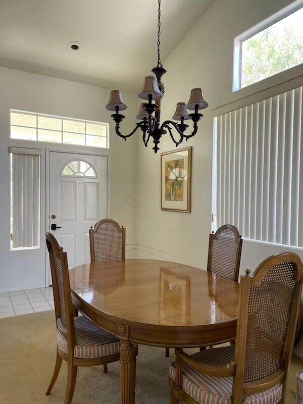 carpeted dining room featuring a chandelier, a wealth of natural light, and vaulted ceiling