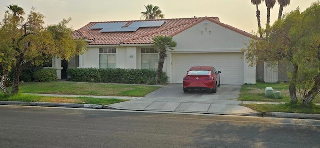 mediterranean / spanish house with solar panels, a lawn, and a garage