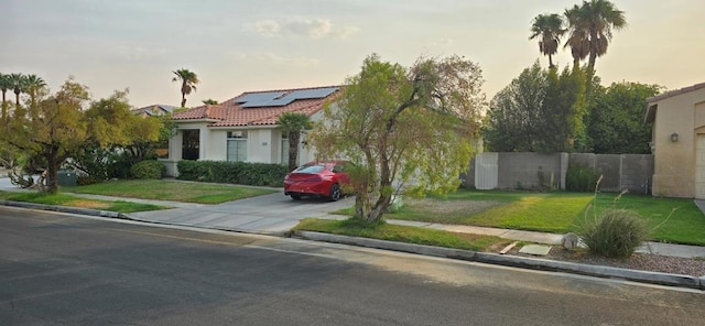 view of front of property featuring a lawn and solar panels