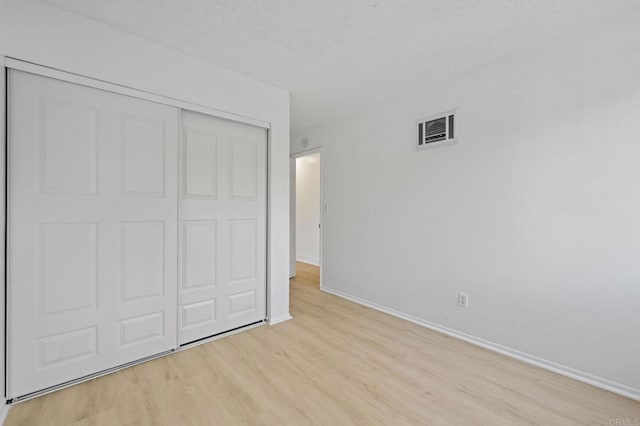unfurnished bedroom with light wood-style floors, baseboards, and a closet