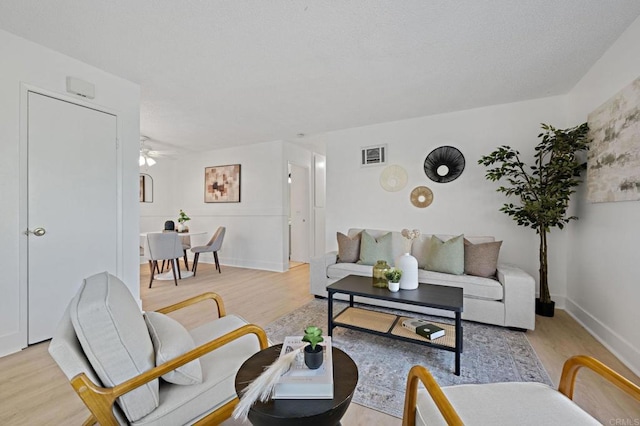 living area featuring light wood-type flooring, a ceiling fan, and baseboards