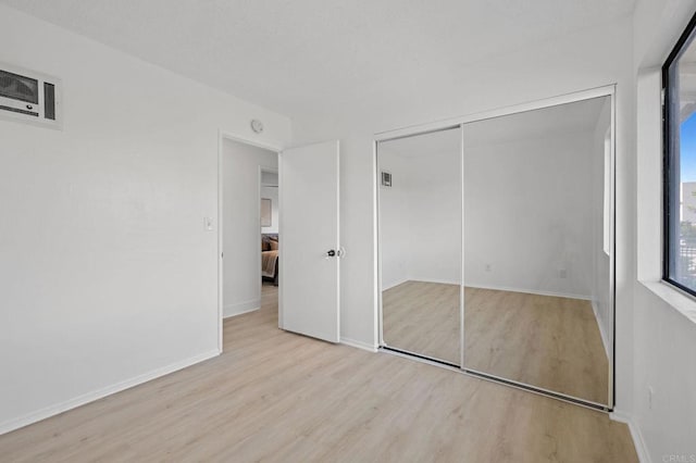 unfurnished bedroom featuring wood finished floors, a closet, and baseboards