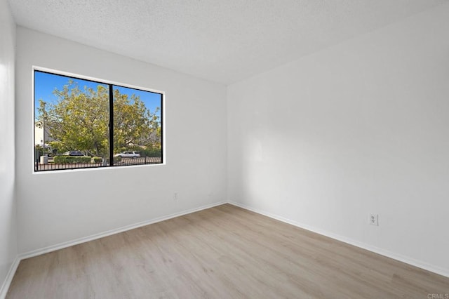 empty room featuring wood finished floors, a textured ceiling, and baseboards