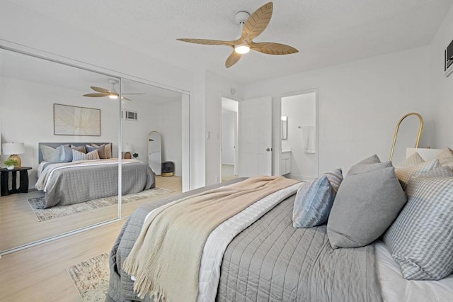 bedroom with light wood-type flooring, a ceiling fan, a closet, and connected bathroom