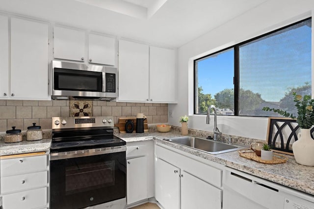 kitchen with stainless steel appliances, a sink, white cabinetry, and decorative backsplash