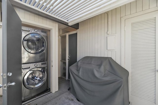 washroom with stacked washer / dryer and wood walls