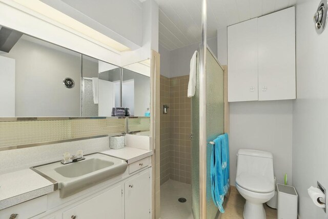 bathroom with decorative backsplash, walk in shower, vanity, tile patterned flooring, and toilet