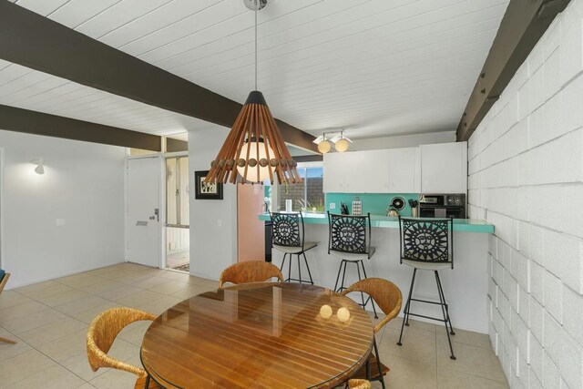 tiled dining area featuring beamed ceiling