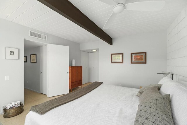 bedroom with ceiling fan, beam ceiling, and light tile patterned floors