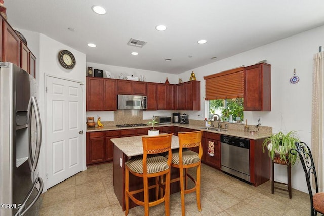 kitchen featuring sink, a breakfast bar, appliances with stainless steel finishes, a center island, and tasteful backsplash