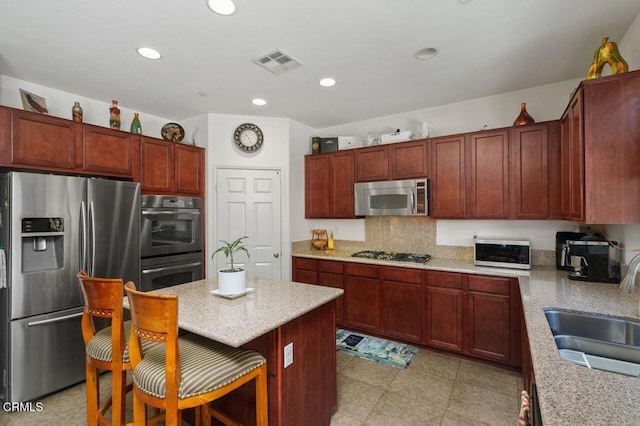 kitchen featuring a kitchen island, sink, backsplash, a kitchen breakfast bar, and stainless steel appliances