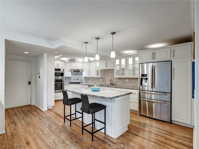 kitchen with a center island, white cabinets, light hardwood / wood-style flooring, appliances with stainless steel finishes, and decorative light fixtures