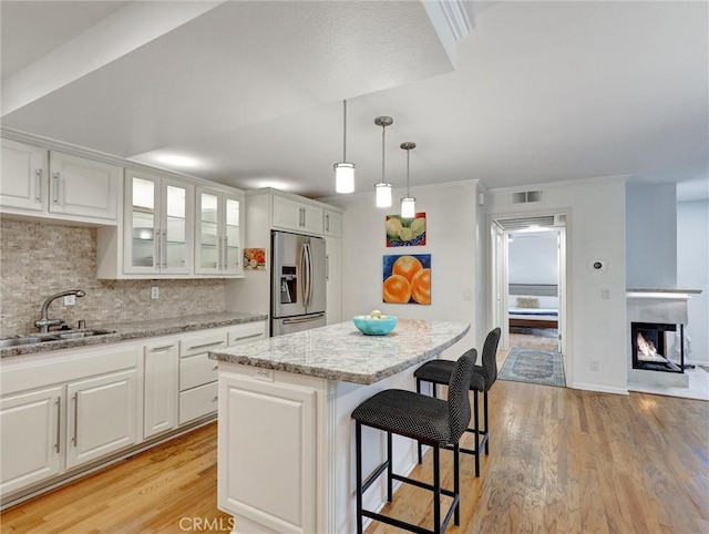 kitchen with white cabinetry, stainless steel fridge, sink, and a kitchen island