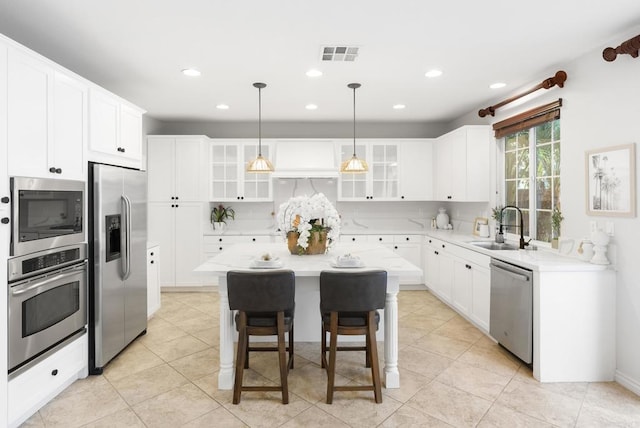 kitchen featuring a center island, sink, a breakfast bar area, stainless steel appliances, and white cabinets