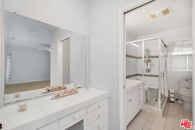 bathroom featuring tile patterned floors, vanity, toilet, and a shower with shower door