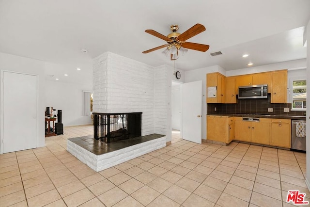 kitchen featuring backsplash, a brick fireplace, light tile patterned floors, and appliances with stainless steel finishes