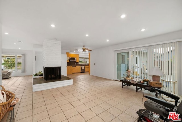 tiled living room with ceiling fan and a fireplace