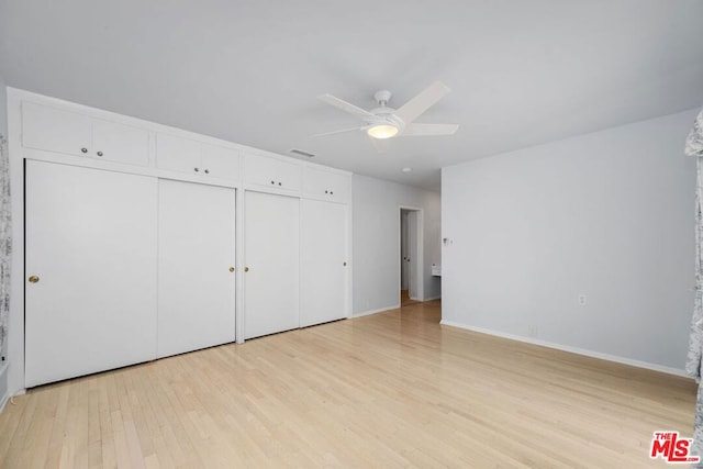 unfurnished bedroom with ceiling fan, light hardwood / wood-style floors, and two closets