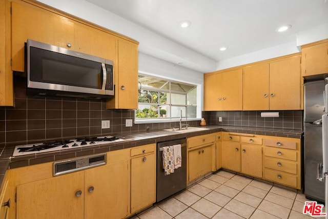 kitchen with appliances with stainless steel finishes, backsplash, sink, light tile patterned floors, and tile counters