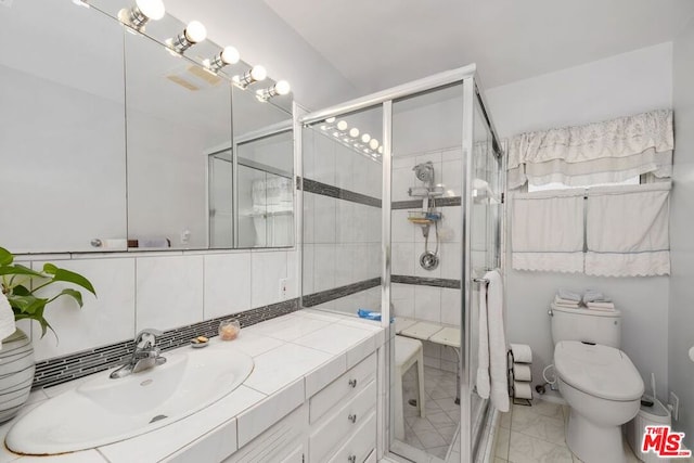 bathroom with vanity, toilet, a shower with shower door, and decorative backsplash