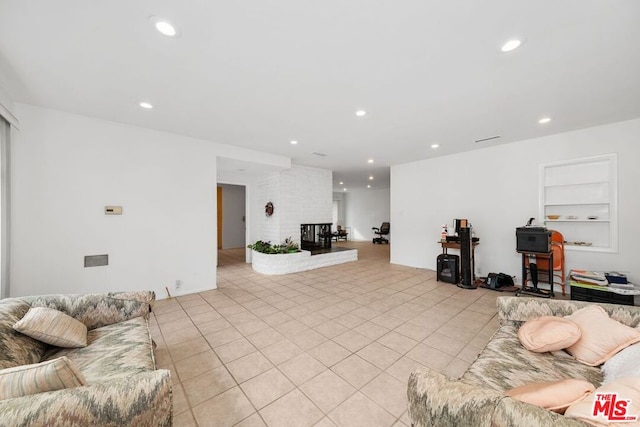 tiled living room featuring a brick fireplace and built in features