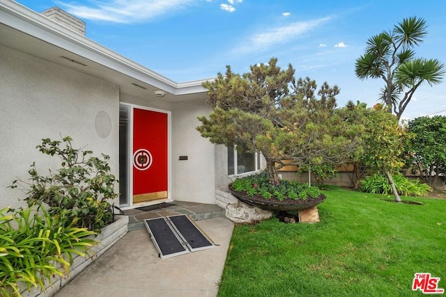 doorway to property with a lawn