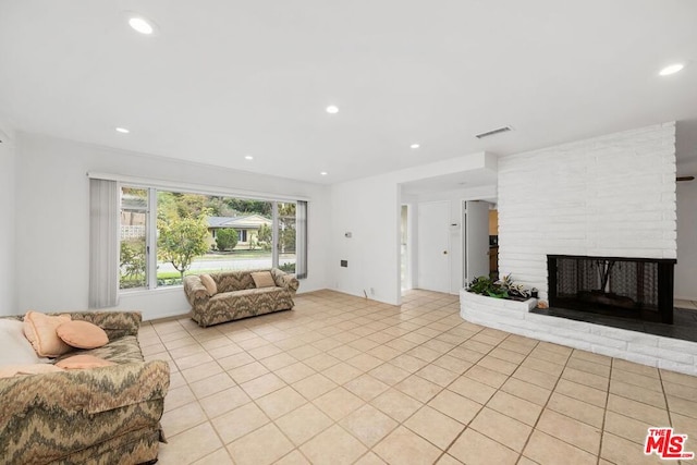 living room with light tile patterned floors and a brick fireplace